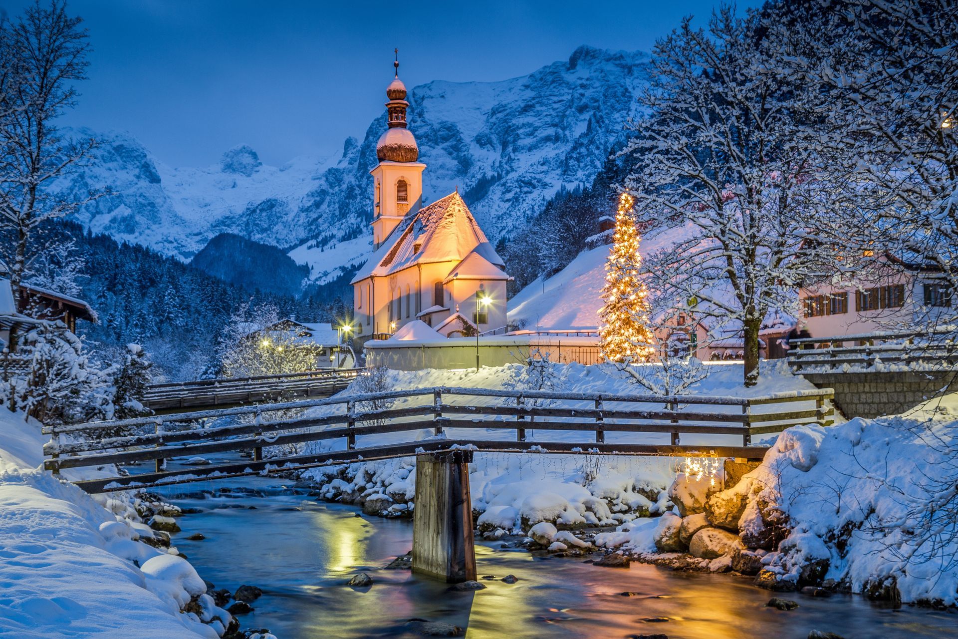 Beautiful twilight view of Sankt Sebastian pilgrimage church with decorated Christmas tree illuminated during blue hour at dusk in winter, Ramsau, Nationalpark Berchtesgadener Land, Bavaria, Germany