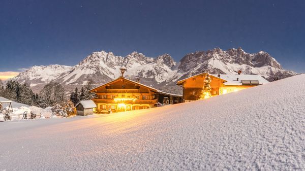 schön beleuchteter Bauernhof mit dem Wilden Kaiser im Hintergru