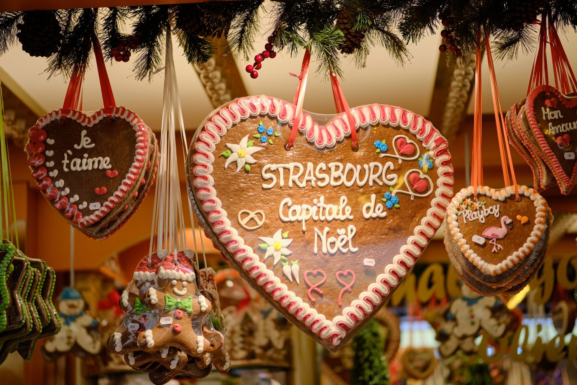 Gingerbread cookies in shape of hearts hanging from stall with messages of Christmas, Love and Strasbourg and a gingerbread man at the Strasbourg Christmas Market