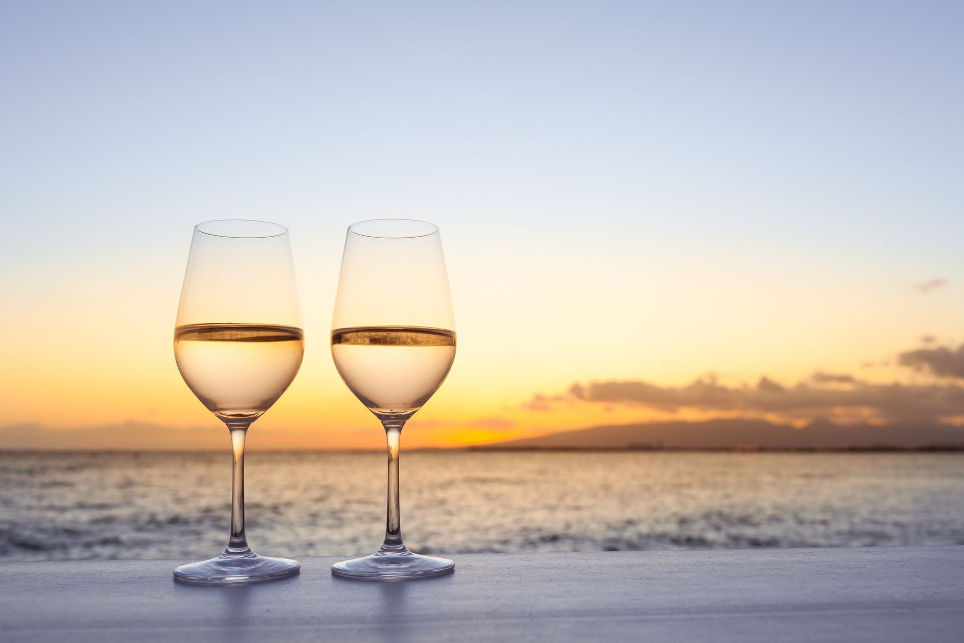 Pair of wine glasses on a bar at sunset. 